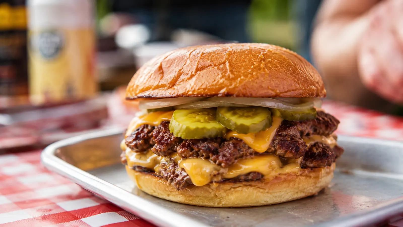 Finished smash burger stacked with American cheese, pickles, and white onion on a toasted potato bun