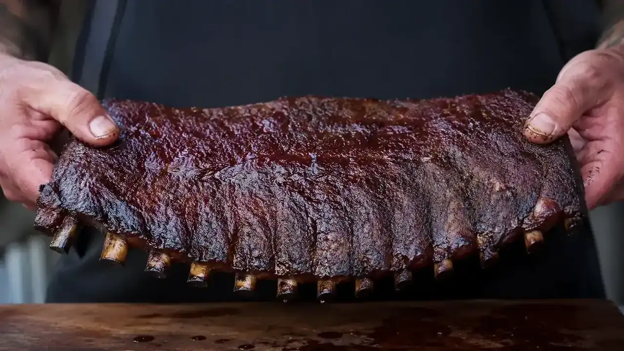 Rack of smoked ribs bending downward in the bend test, showing flexible pull-back meat