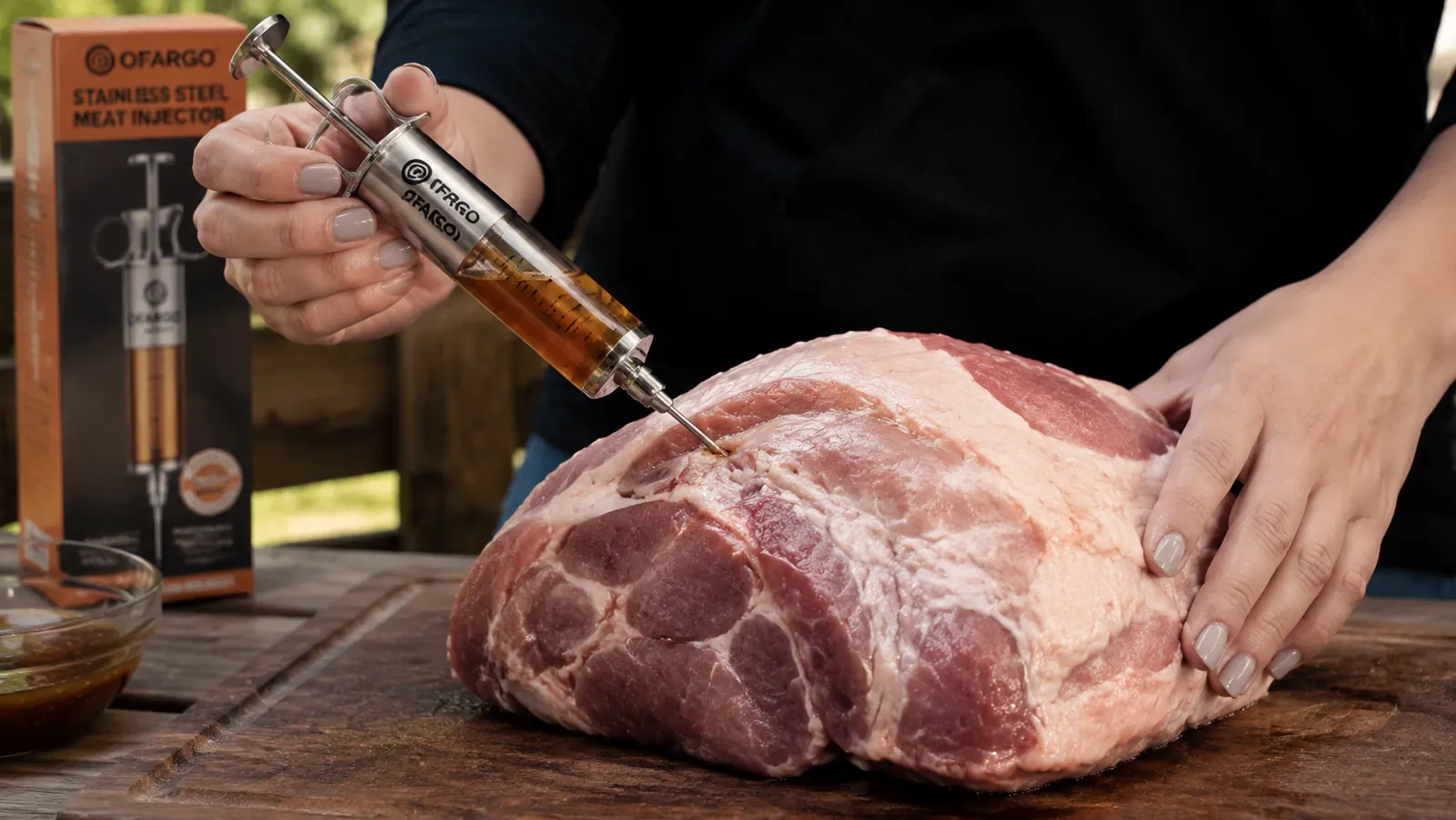 Close-up of a hand pushing the plunger of a meat injector syringe into a pork shoulder on a cutting board, marinade visible inside the barrel