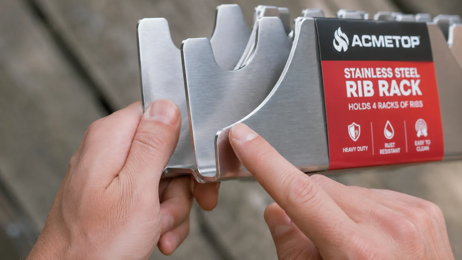 Close-up of fingers touching the sharp slotted edges of a stainless steel rib rack, showing the raw metal edges between the slots