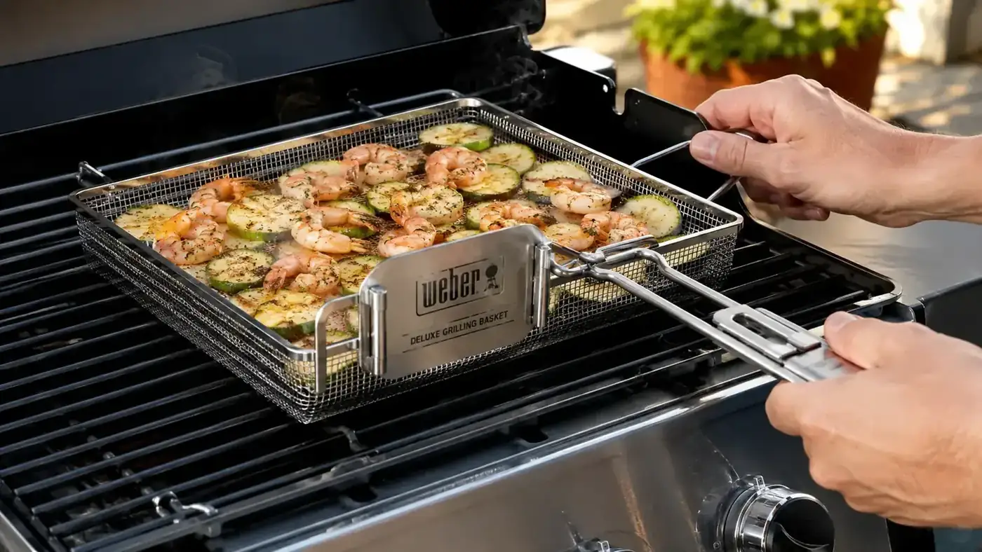 Weber Deluxe Grilling Basket filled with shrimp and zucchini on a hot gas grill